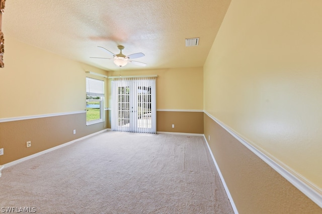 carpeted spare room featuring ceiling fan, french doors, and a textured ceiling