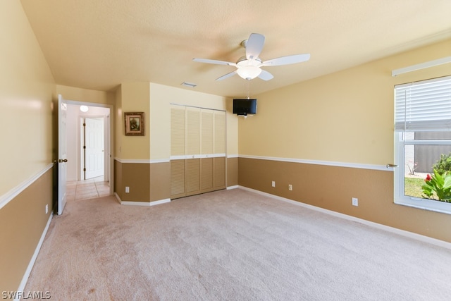 unfurnished bedroom with light colored carpet, ceiling fan, and a closet