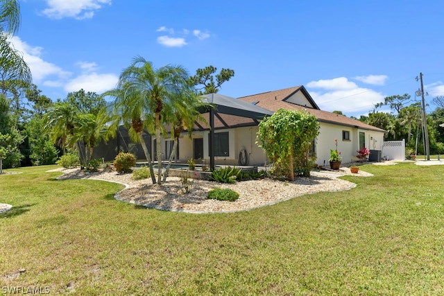 back of house with a lanai and a lawn