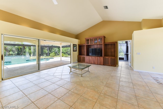 unfurnished living room featuring high vaulted ceiling and light tile floors