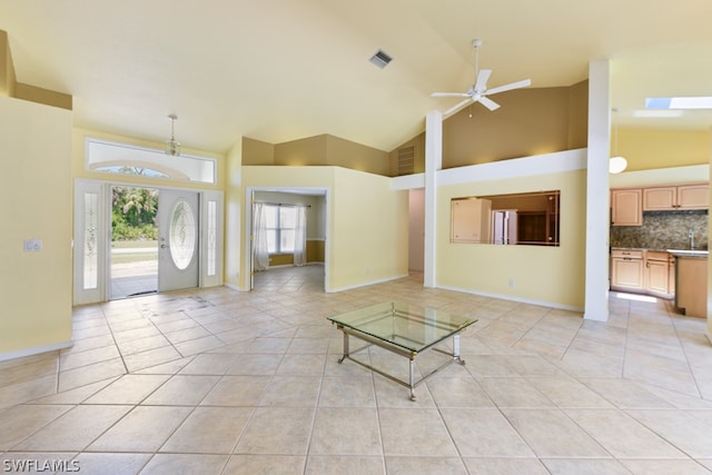 unfurnished living room with high vaulted ceiling, ceiling fan, and light tile floors