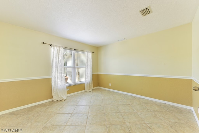 tiled empty room with a textured ceiling