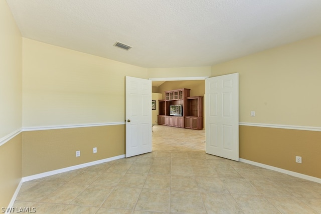 unfurnished room featuring light tile floors and a textured ceiling