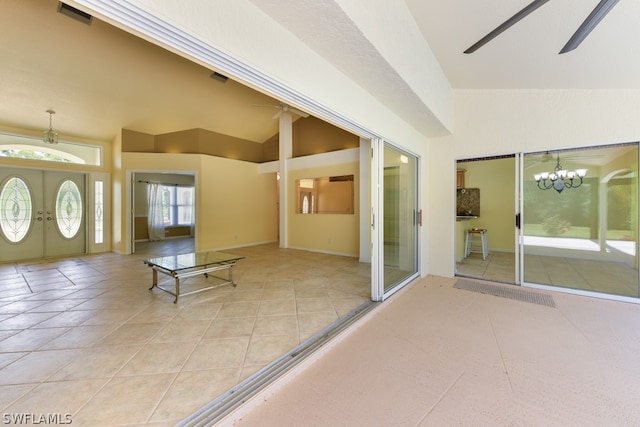 interior space with vaulted ceiling, french doors, ceiling fan with notable chandelier, and light tile floors