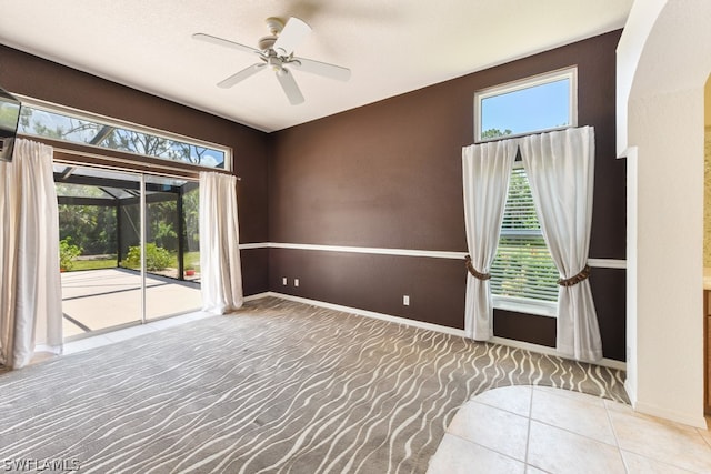 carpeted spare room featuring plenty of natural light and ceiling fan