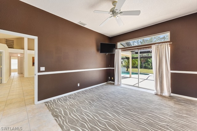 spare room featuring a textured ceiling, ceiling fan, and light carpet