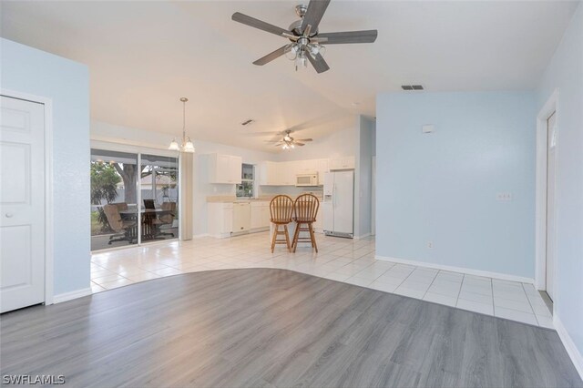 unfurnished living room featuring light hardwood / wood-style floors, ceiling fan with notable chandelier, and vaulted ceiling