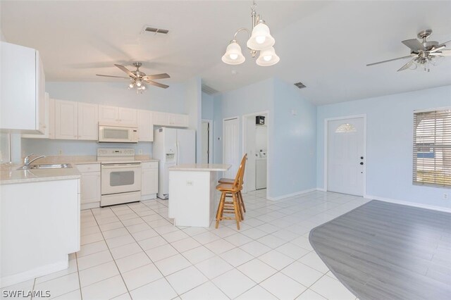 kitchen with sink, a kitchen island, white cabinetry, and white appliances