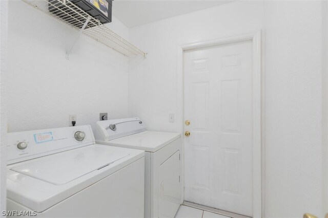 laundry room featuring washing machine and clothes dryer and light tile patterned floors