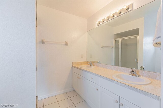 bathroom featuring a shower with door, tile patterned floors, and vanity