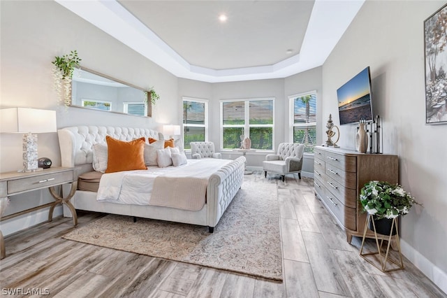 bedroom featuring light hardwood / wood-style floors and a raised ceiling