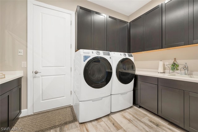 laundry area with independent washer and dryer, light hardwood / wood-style floors, cabinets, and sink