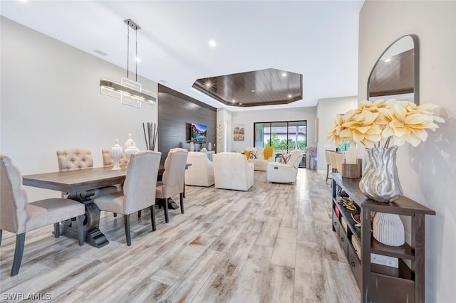 dining room with light hardwood / wood-style floors and a tray ceiling