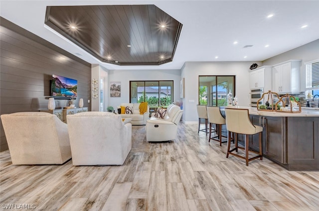 living room featuring light hardwood / wood-style flooring and a tray ceiling