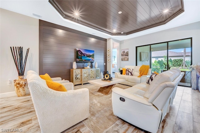 living room featuring a raised ceiling and light hardwood / wood-style floors