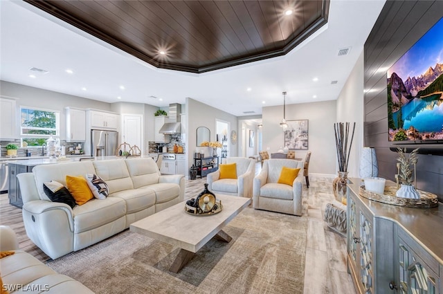 living room featuring a raised ceiling and light wood-type flooring