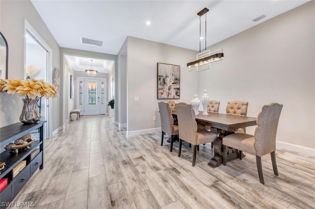 dining space featuring light hardwood / wood-style flooring and a tray ceiling