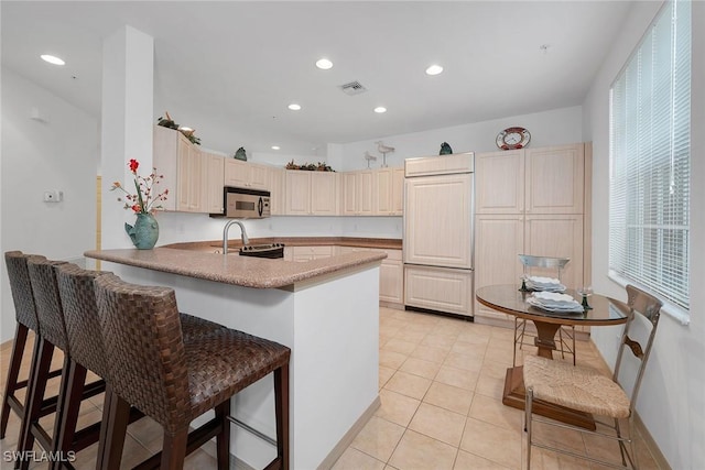 kitchen with light tile patterned floors, a breakfast bar, kitchen peninsula, and appliances with stainless steel finishes