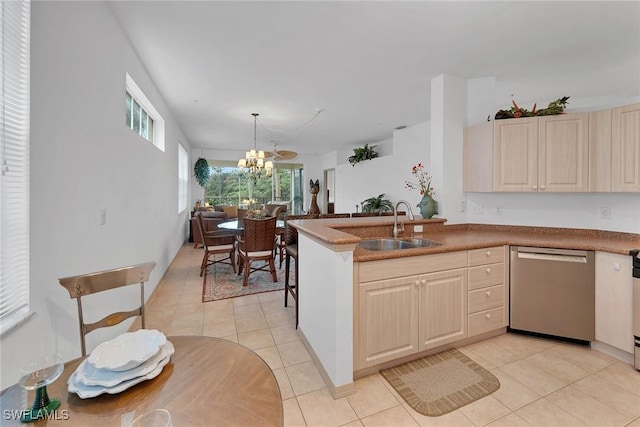 kitchen featuring pendant lighting, sink, light tile patterned flooring, stainless steel dishwasher, and a chandelier