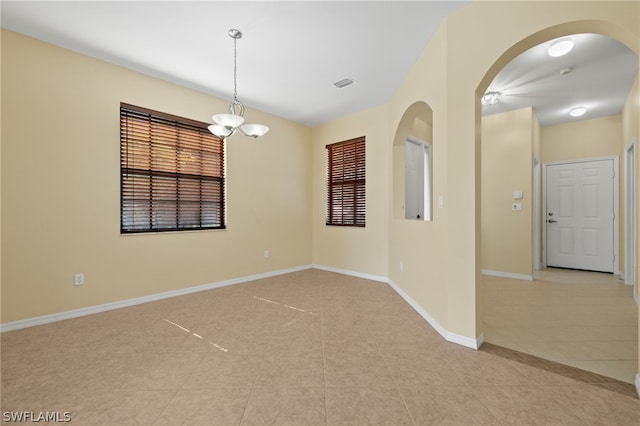 spare room with a chandelier and light tile floors