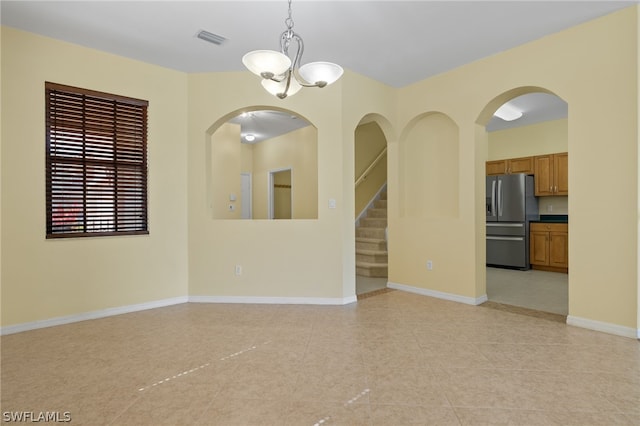 spare room with an inviting chandelier and light tile flooring