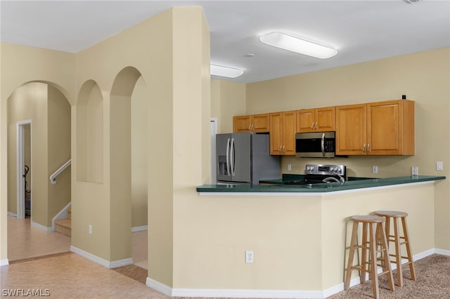 kitchen featuring a kitchen breakfast bar, stainless steel appliances, and light tile floors