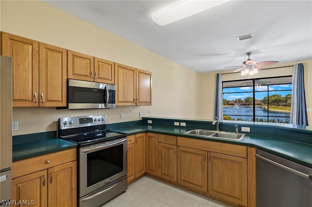 kitchen featuring stainless steel appliances, a water view, sink, ceiling fan, and light tile floors