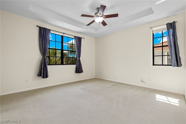 carpeted empty room featuring a tray ceiling and ceiling fan