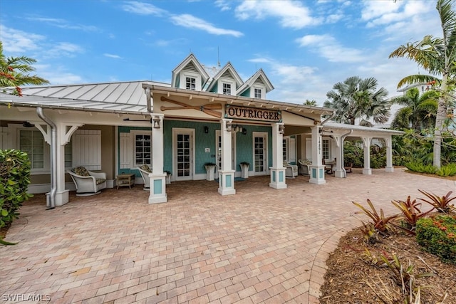 back of property with a standing seam roof, a patio area, and metal roof