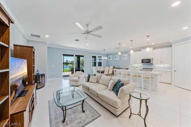 living area with light tile patterned floors, baseboards, visible vents, recessed lighting, and crown molding