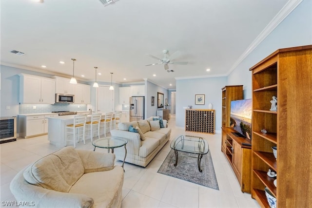 living area featuring light tile patterned floors, visible vents, ceiling fan, and crown molding