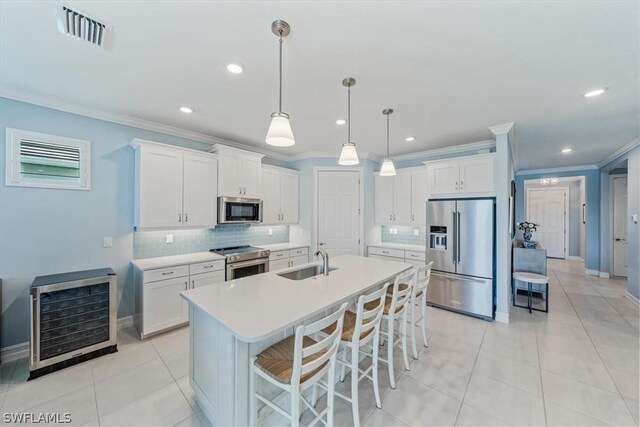 kitchen featuring appliances with stainless steel finishes, white cabinetry, sink, a kitchen breakfast bar, and a kitchen island with sink