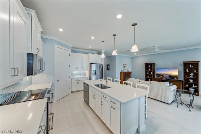 kitchen with appliances with stainless steel finishes, sink, ceiling fan, an island with sink, and pendant lighting