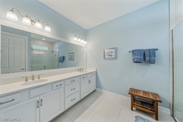 full bath featuring double vanity, a stall shower, baseboards, and a sink