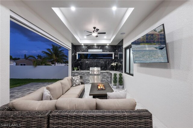 living room with ceiling fan and a tray ceiling