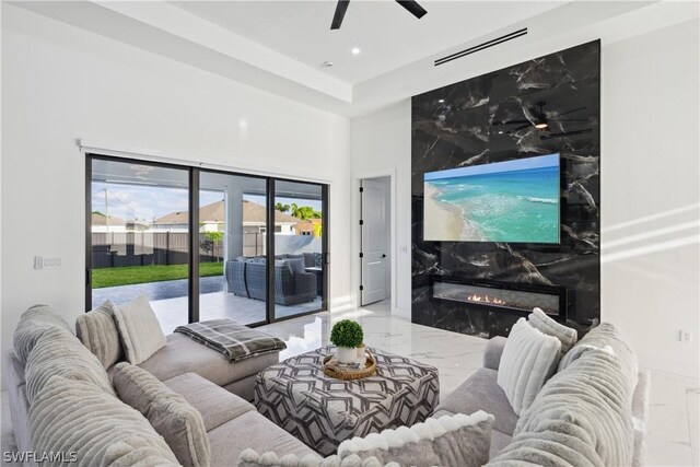 living room with a high end fireplace and ceiling fan