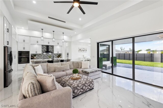 living room featuring sink, a raised ceiling, and ceiling fan