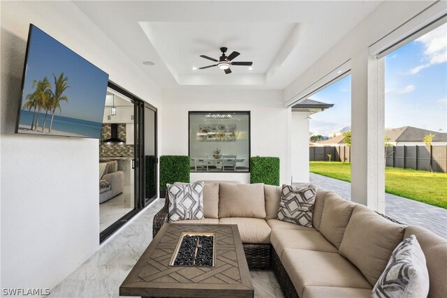 sunroom featuring ceiling fan and a tray ceiling