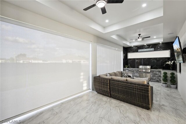 sunroom featuring ceiling fan and a tray ceiling