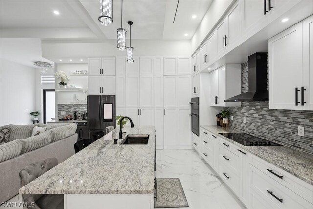 kitchen featuring white cabinetry, wall chimney range hood, black appliances, and a spacious island