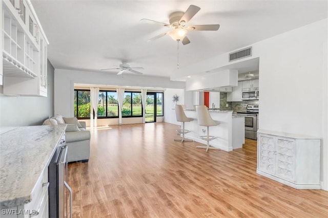 living room featuring ceiling fan, light hardwood / wood-style flooring, and sink