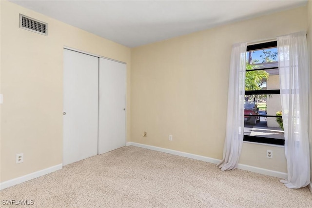 unfurnished bedroom with light colored carpet and a closet