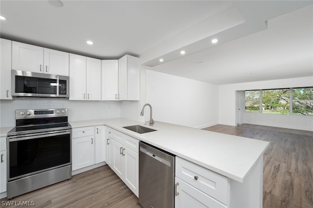 kitchen with kitchen peninsula, stainless steel appliances, white cabinetry, and sink