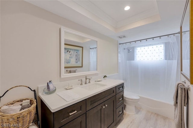 full bathroom featuring shower / bath combo, vanity, hardwood / wood-style floors, a raised ceiling, and toilet