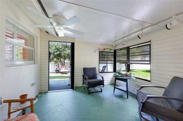 sunroom / solarium featuring rail lighting, plenty of natural light, and ceiling fan