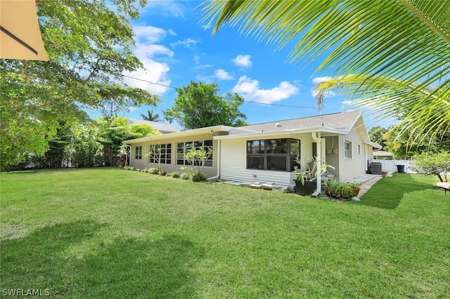 back of house with a yard and central AC