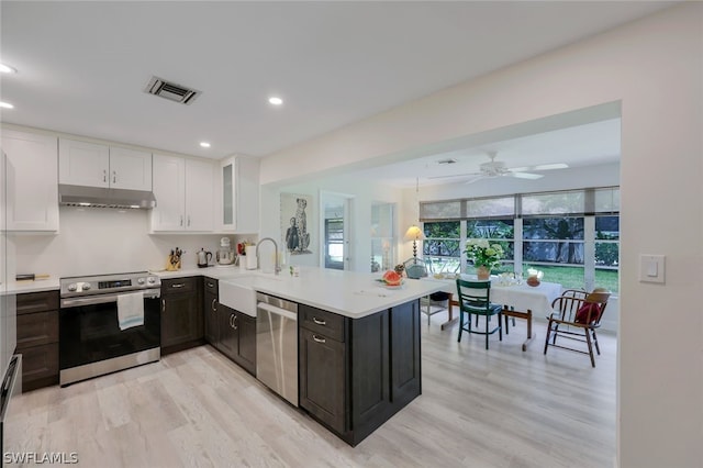 kitchen featuring kitchen peninsula, stainless steel appliances, white cabinetry, and light wood-type flooring