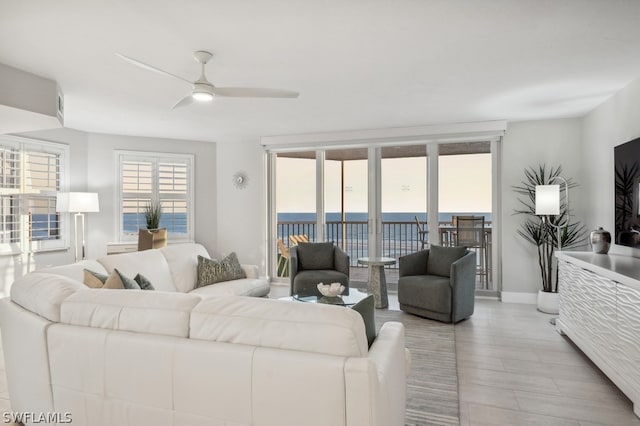 living room with ceiling fan, light hardwood / wood-style floors, and a water view