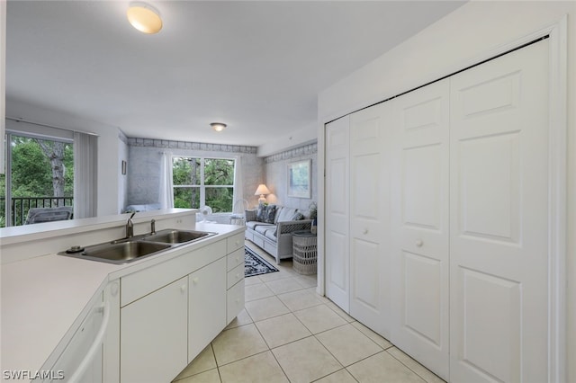 kitchen featuring sink, light tile flooring, white cabinetry, and a wealth of natural light