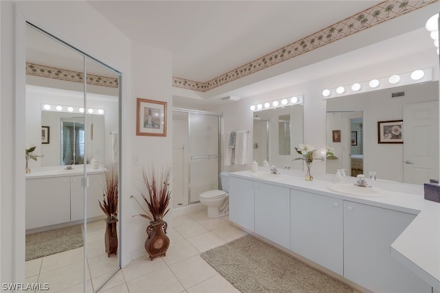 bathroom with tile floors, vanity with extensive cabinet space, toilet, and double sink